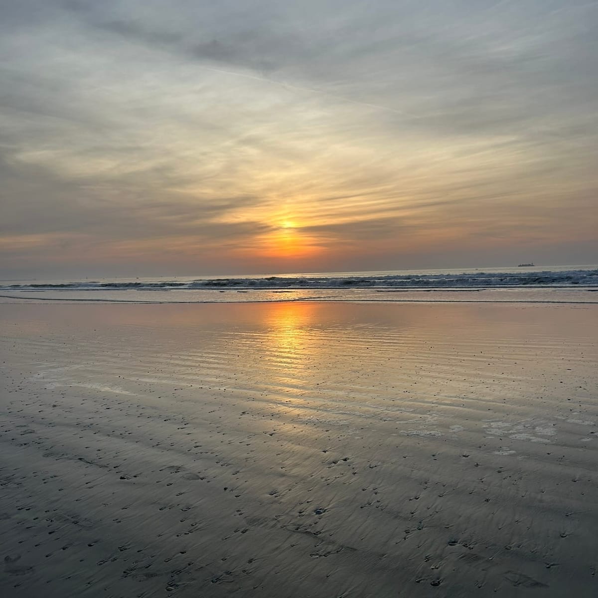 A sunrise on the ocean with orange, blue, and gray tones