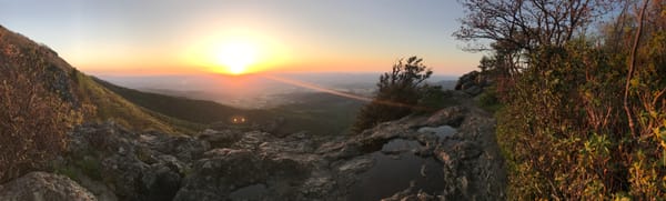 A panoramic view of mountains with a vibrant sunset casting warm colors across the sky
